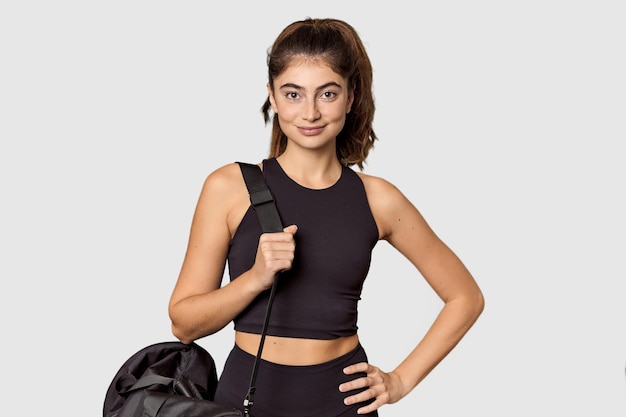 Cheerful Caucasian athlete with gym backpack in studio