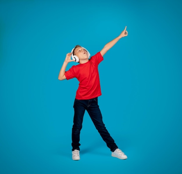 Cheerful caucasian boy wearing wireless headphones listening music and dancing