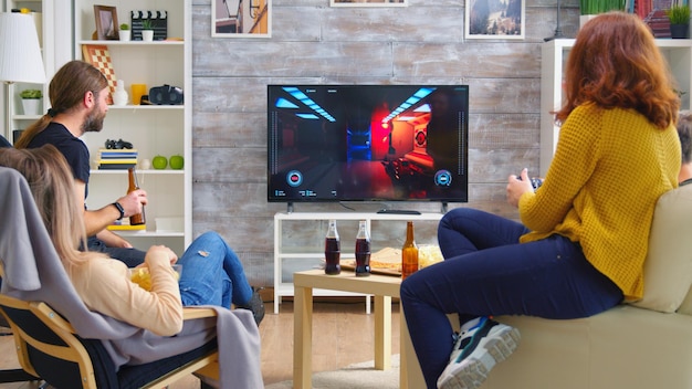 Cheerful caucasian friends playing video games on big tv in living room.