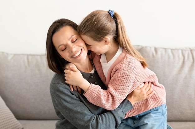 Cheerful caucasian middle aged mother hugs little daughter enjoy tender moment in weekend