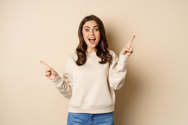 Cheerful caucasian woman showing directions two ways pointing\
sideways at variants choices for custo...