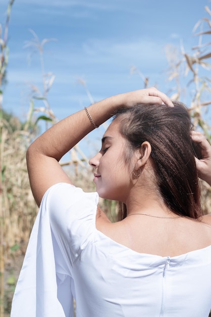 Donna caucasica allegra in abito bianco sullo sfondo del cielo del raccolto di mais