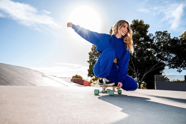 Photo cheerful caucasian woman with blonde hair skating in urban setting