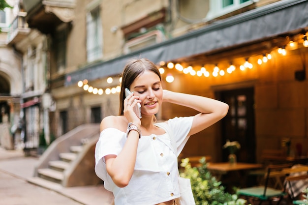 Allegra donna carismatica parla al telefono mentre si cammina la sera lungo la strada della città vecchia