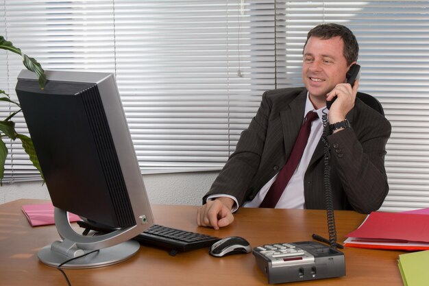 Cheerful and charming man in office answering the phone