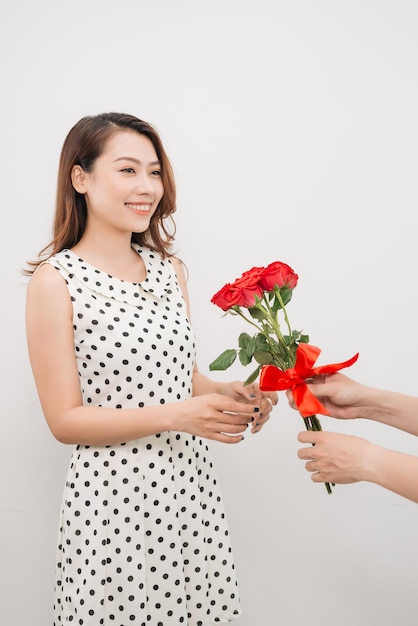 Cheerful charming young woman receiving bunch of flowers from her boyfriend over white background