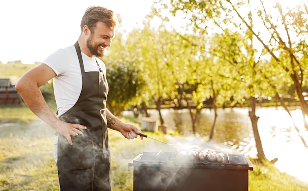 Cheerful chef frying meat on grill