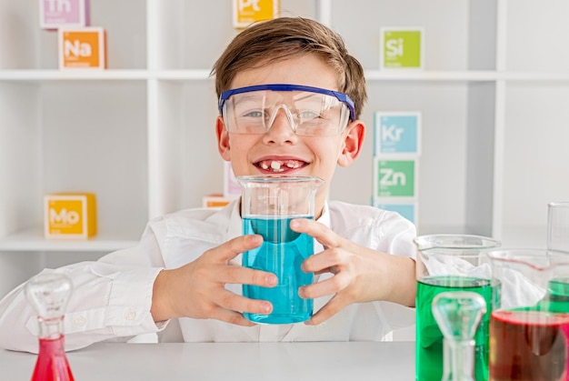 Cheerful chemist presenting flask with blue mixture