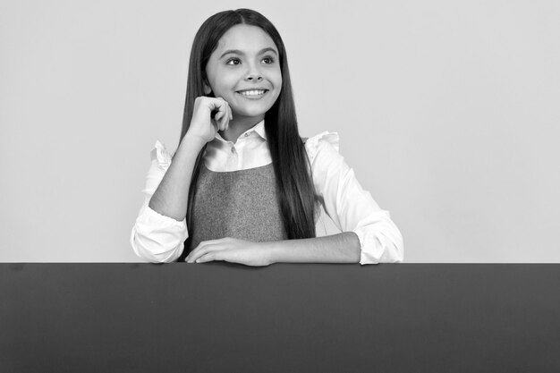 Cheerful child behind blank pink paper sheet for copy space announcement