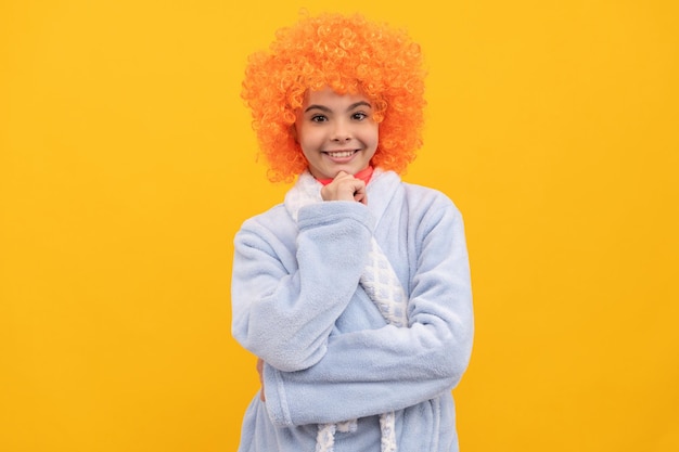 Cheerful child in fancy orange wig hair wear home bathrobe, morning