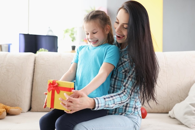 陽気な子の女の子がプレゼントボックスを開いて、幸せな感情を表現します