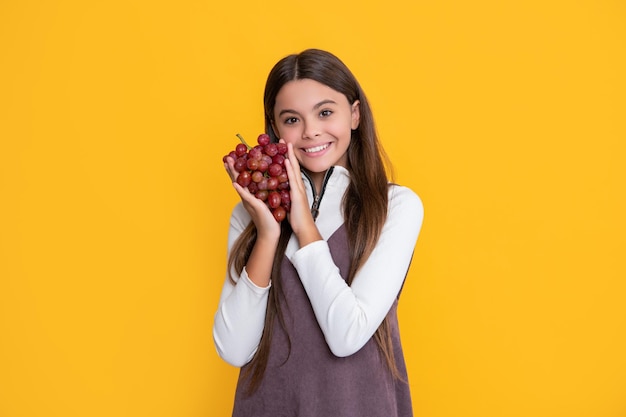 Cheerful child hold fresh grape fruit on yellow background