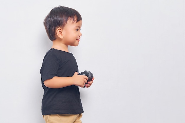 Cheerful child kid boy 2 years wearing black tshirt play pc game with joystick console isolated on white background