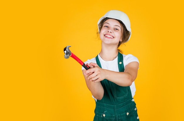 Cheerful child laborer using building uniform and hammer tool tool shop