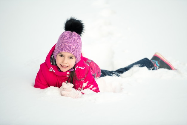 雪の中で横たわっている陽気な子供