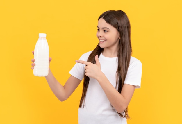 Cheerful child point finger on dairy beverage product teen girl going to drink milk