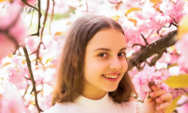 Bambino allegro alla fioritura del fiore di sakura in primavera