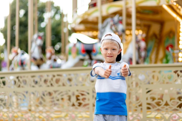 Il bambino allegro cammina in un parco di divertimenti