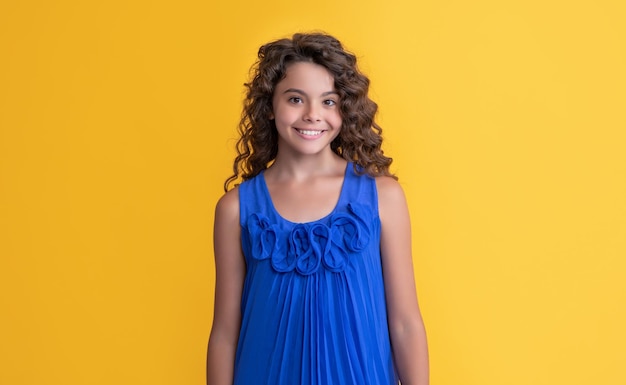 Cheerful child with long brunette afro hair on yellow background