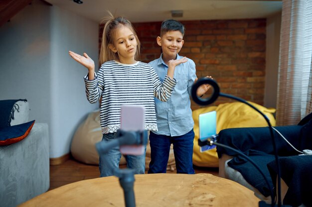 Cheerful children bloggers dance on camera, little vloggers