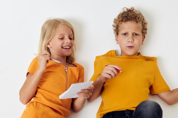 Cheerful children emotions drawing together notepad and pencils light background unaltered