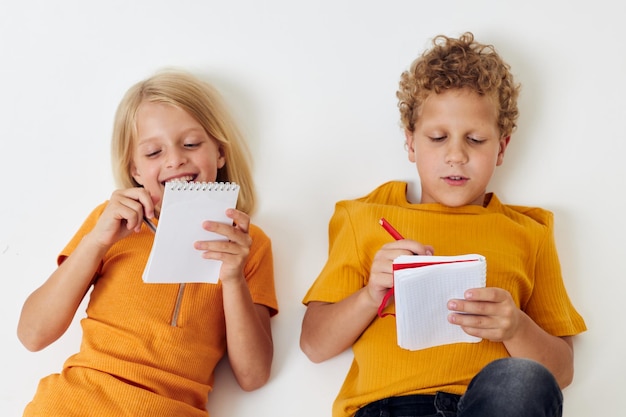 Cheerful children emotions drawing together notepad and pencils light background unaltered