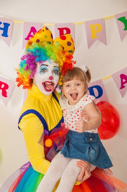 楽しんでいる誕生日の女の子と休日の陽気なピエロの女の子