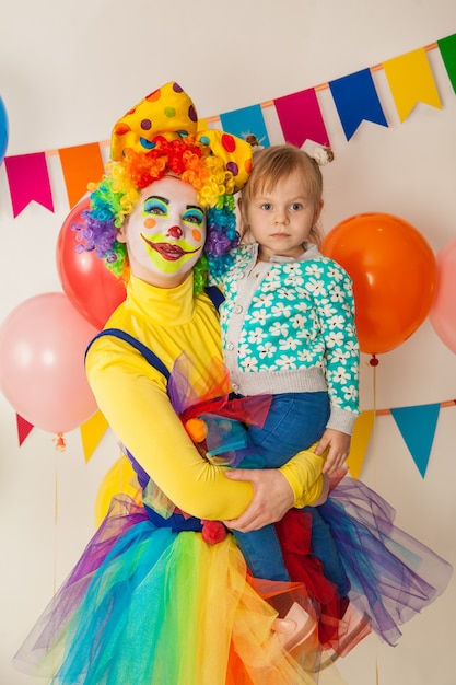 Cheerful clown with a kid at a colorful party