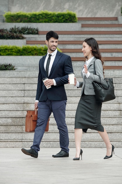 Cheerful colleagues drinking coffee going to work and discussing project details