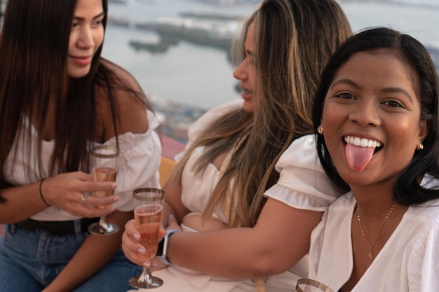 Cheerful colleagues with glasses of alcoholic beverages sharing during the festive rooftop event