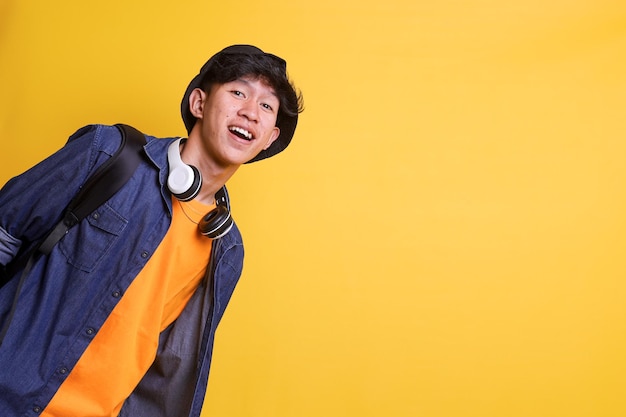 Cheerful college young man wear bucket hat backpack and casual clothes with headphones on his neck