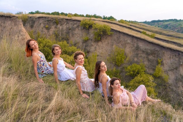 A cheerful company of beautiful girls friends enjoy a picturesque panorama of the green hills