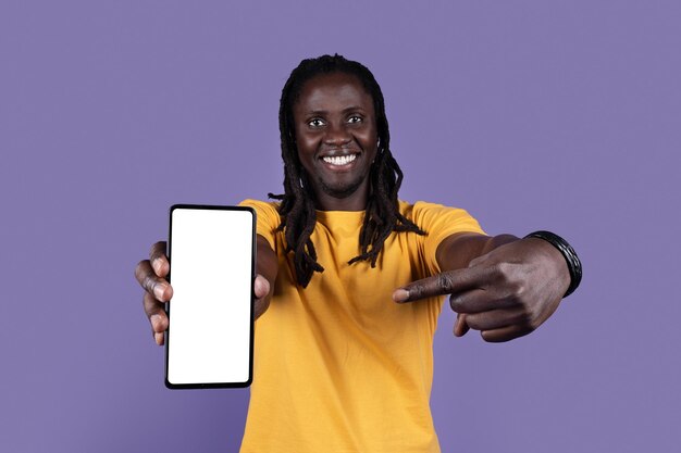 Cheerful cool black guy pointing at cell phone mockup