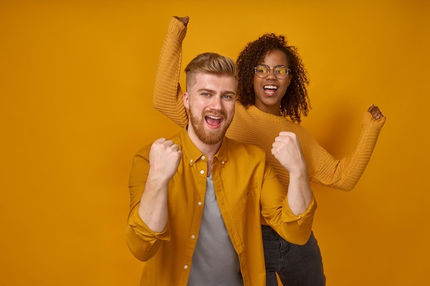 Cheerful couple clenching fists like winners or happy to achieve goal