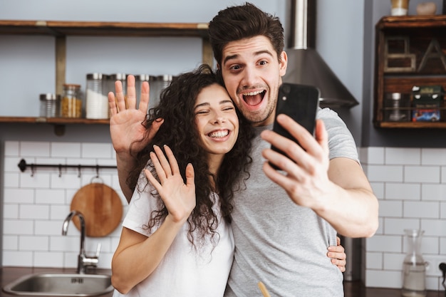 Cheerful couple cooking at the kitchen, having fun, taking a selfie