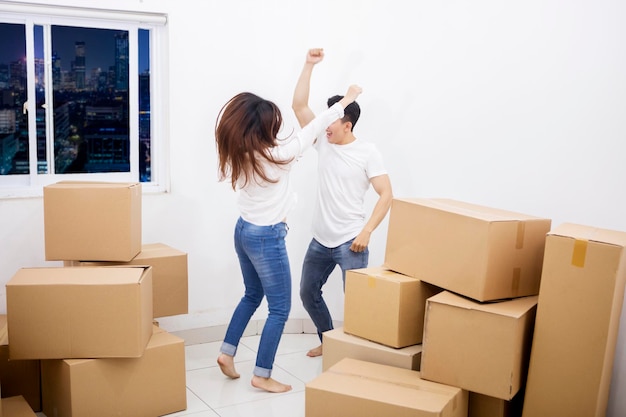 Cheerful couple dances near piles of boxes