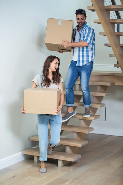 Cheerful couple holding cardboard boxes on steps 