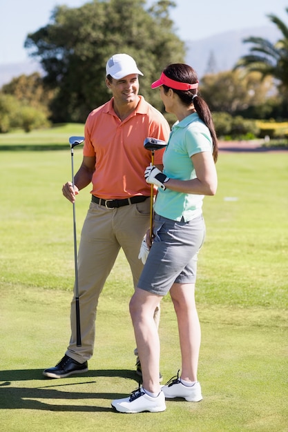 Cheerful couple holding golf clubs