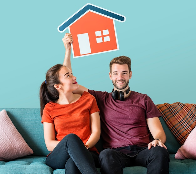 Cheerful couple holding a house icon