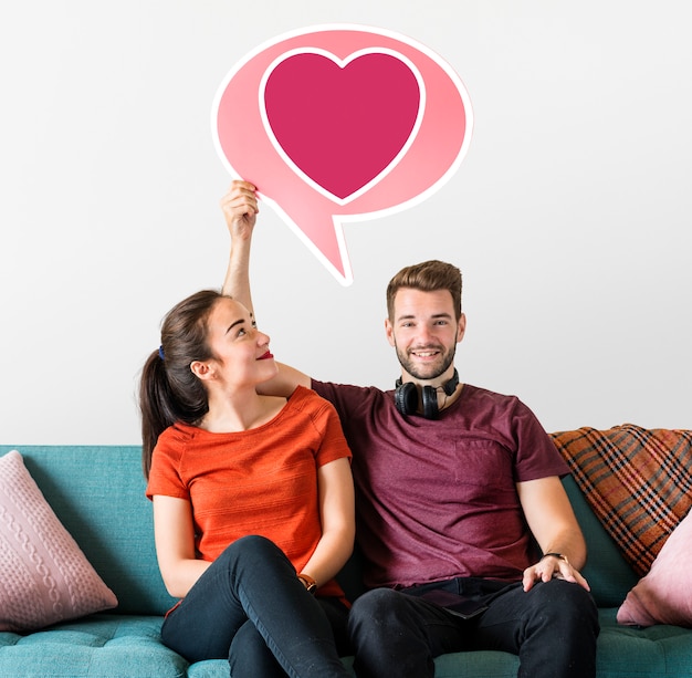 Cheerful couple holding a speech bubble with heart icon