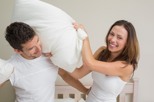 Photo cheerful couple pillow fighting in bed