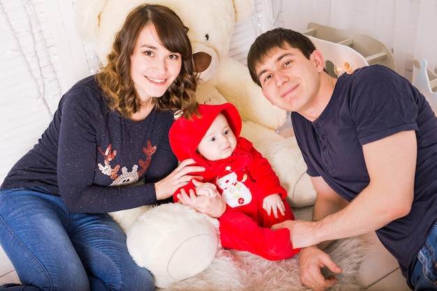 Cheerful couple playing with baby boy at home.