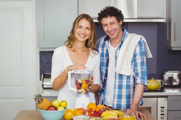 Cheerful couple preparing a fruit juice 