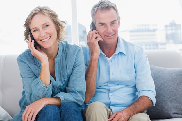 Cheerful couple on their mobile phones on the couch