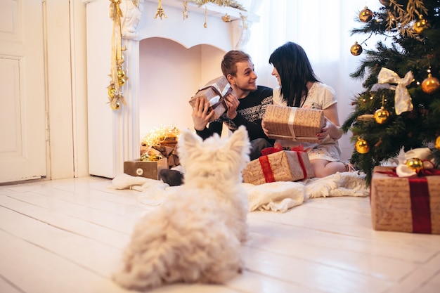 "Cheerful couple with dog opening presents"