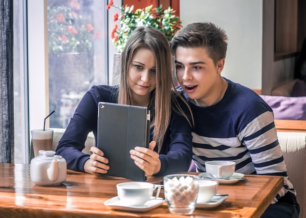 Cheerful couple with tablet wondering, shocked.