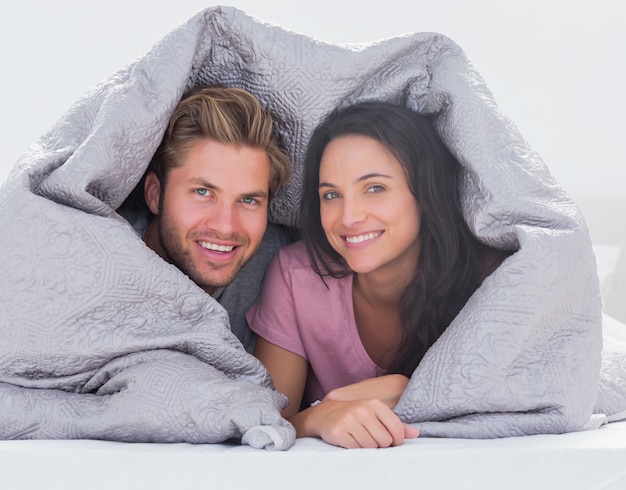 Cheerful couple wrapped in the duvet