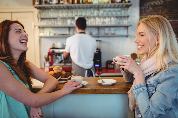 Cheerful customers talking at counter in coffee shop