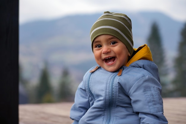 Neonato sveglio allegro che ride mentre sedendosi all'aperto bambino adorabile felice che sorride all'aperto