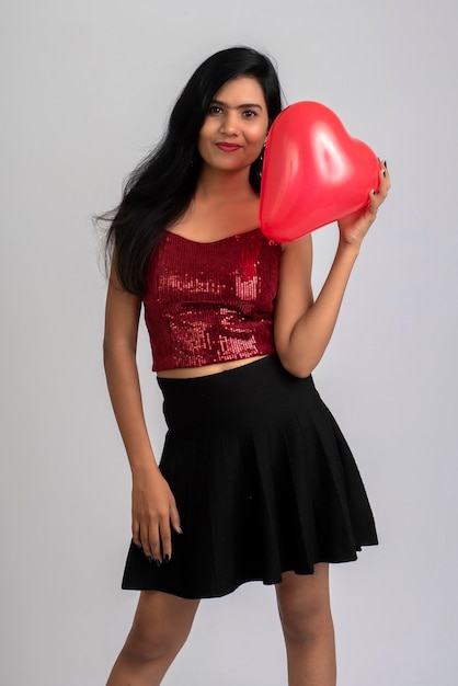 Cheerful cute girl in fancy outfit posing with heart shape balloon